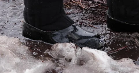 A man walks along a flowing stream in the slush Stock Footage 150397351