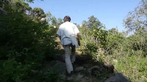 Man walks along a mountain path in Sunny day Stock Footage 69256157