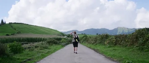 A man walks along a path leading to Twin Lakes in a volcanic crater Stock Footage 320976248