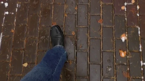 A man walks along a path in a park in autumn - Fallen leaves and snow - Top view 動画素材 81721454