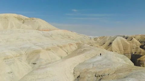 A man walks along a path that runs along the ridge of desert mountains Stock Footage 234617812