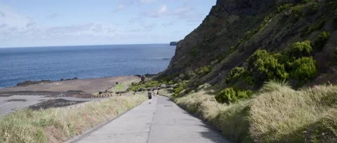 A man walks along a path towards the Ponta da Ferraria Stock Footage 320074063