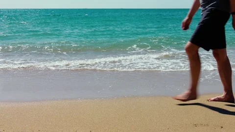 Man walks along a sandy beach Stock Footage 132428335