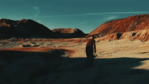 A man walks along a sandy, dried-up valley against the background of rocks. Stock Footage 160364981