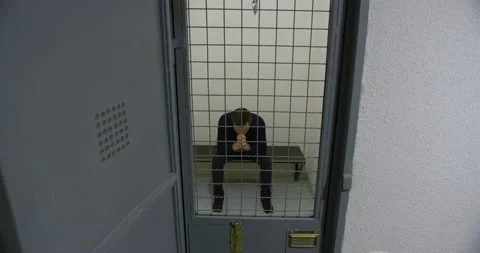 A man walks around the prison cell from side to side. Offender Stock Footage 168372350