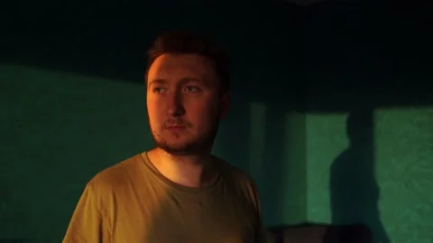 A man walks around the room, hears strange sounds, looks around with displeasure Stock Footage 157118729
