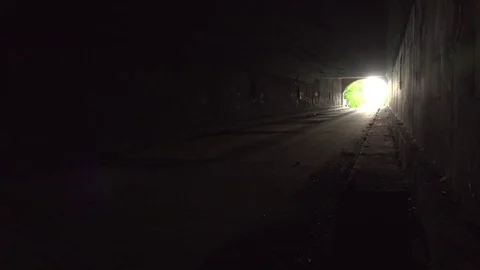 Man walks away from camera through dark tunnel with hands spanned open Stock Footage 70172583