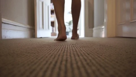 Man walks away down carpeted corridor in home, low angle fixed shot from 스톡 동영상 120377863