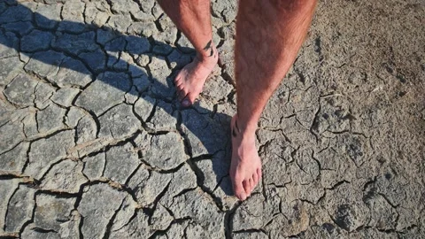 A man walks barefoot through mud and swampy cracked earth. 動画素材 319050247