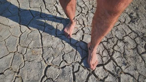 A man walks barefoot through mud and swampy cracked earth. Stock Photos