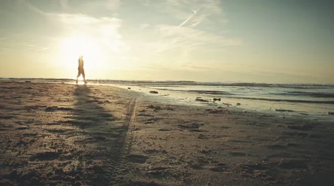 Man walks on beach during sunset, graded Stock Footage 57390549