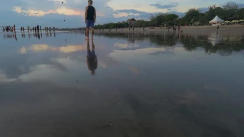 Man walks on beach in low tide with reflections Stock Footage 153732106