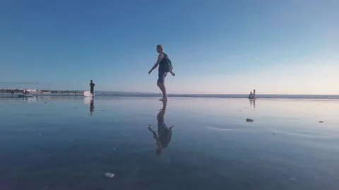 Man walks on beach in low tide with reflections Stock Footage 154424418