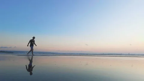 Man walks on beach in low tide with reflections Stock Footage 154550336