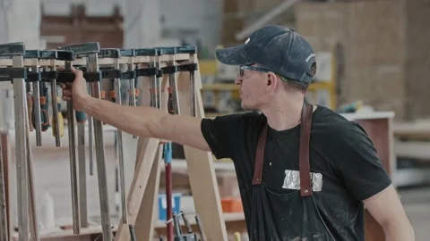 Man walks in a carpentry workshop and takes an instrument - looking in the Stock Footage 157035276