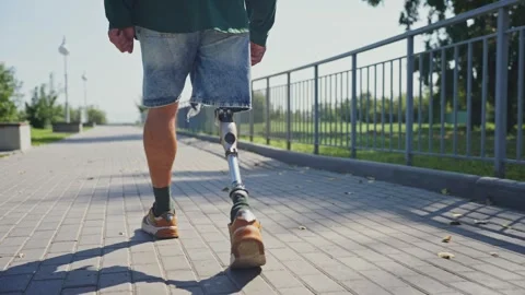 Man walks confidently on a sunny day with a prosthetic leg in the park 스톡 동영상 287191153