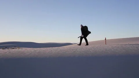 Man walks into desert against setting sun Stock Footage 82507584
