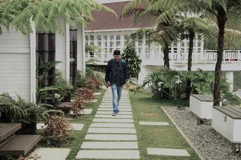 A man walks down a path in front of a house Stock Photos