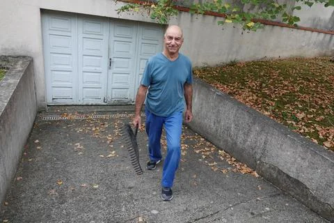 Man walks down a path with a rake in hand Stock Photos