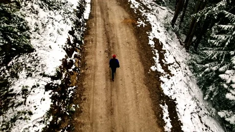 Man walks down the road. Followed by drone. Winter road. Steps. Tracking. Allone Stock Footage 218793937