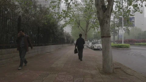 Man Walks Down The Sidewalk in Henan, China on a Smoggy Polluted Day Stock Footage 130866794