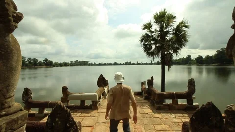 Man walks down stairs toward temple lake, then comes back, Sras Srang lake Stock Footage 76381908