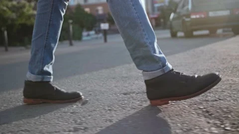 A man walks down the street at sunset with a close-up of his feet Stock Footage 155336413
