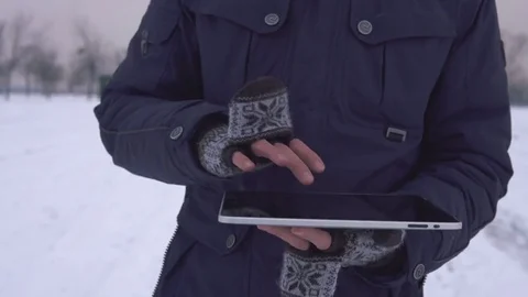 A man walks down the street in winter and uses a tablet Stock Footage 83728779