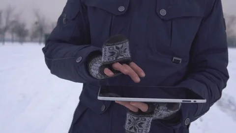 A man walks down the street in winter and uses a tablet Stock Footage 83728784
