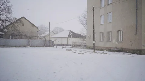 A man walks down a street in the winter, while it is snowing. Video stock 126724486