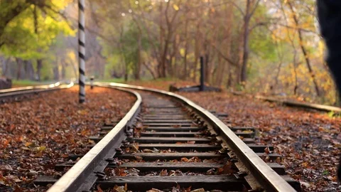A man walks down train rails on a background golden Autumn forest. A man departs Stock Footage 83370393