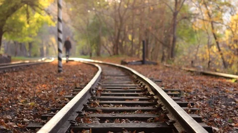 A man walks down train tracks on a background golden Autumn forest. A man 스톡 동영상 83368251