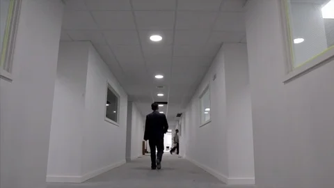 Man walks down a white corridor in an office building 스톡 동영상 78771455