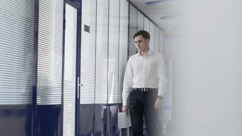 Man walks down a white glass corridor in an under construction office building Vídeos de archivo 122044344