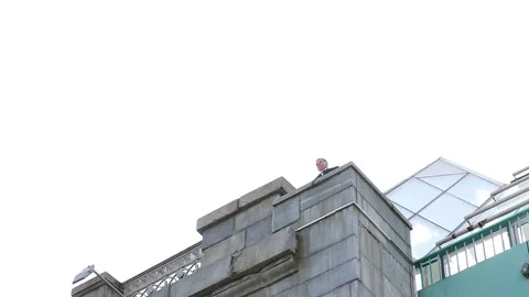 The man walks to the edge of the bridge and looks down. Shooting from the ground Stock Footage 80356050