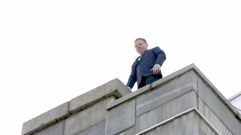 The man walks to the edge of the bridge and looks down. Shooting from the ground Stock Footage 80356051