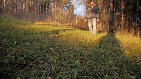 Man walks on forest glade at sunset 스톡 동영상 168460485