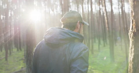 A man walks in the forest at sunrise, rays breaking through the branches of Vídeo Stock 169562968