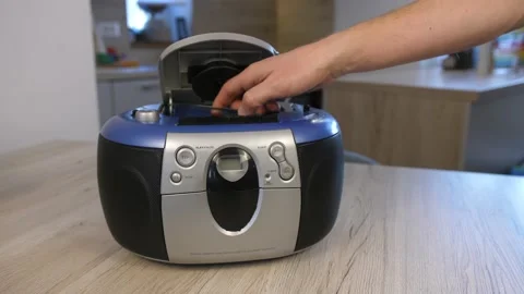 Man walks in frame and inserts cd in retro radio, pushes play, static Stock Footage 171378745