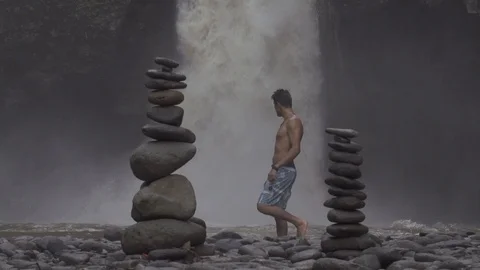 Man Walks in Front of Waterfall Bali Stock Footage 106152295