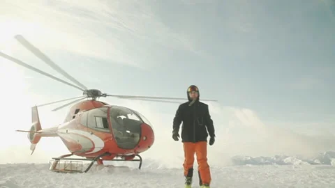 A man walks in front of a working helicopter on top of a mountain. Stock Footage 196275304