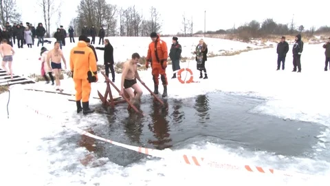 A man walks into a hole in the shape of a cross. Dipping in cold water at a reli Stock Footage 101283393
