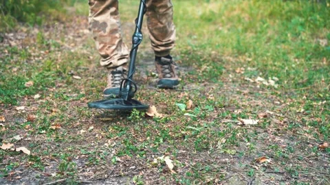 Man walks with a metal detector through the forest and looks for metal Stock Footage