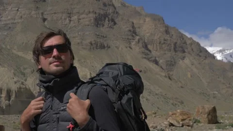 A man walks in the mountains with a backpack Stock Footage 141787393