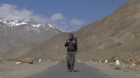 A man walks in the mountains with a backpack Stock Footage 141787409