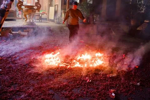 Man walks past burning firecracker debris at Shezidao Earth God Lantern Fes.. Stock Photos