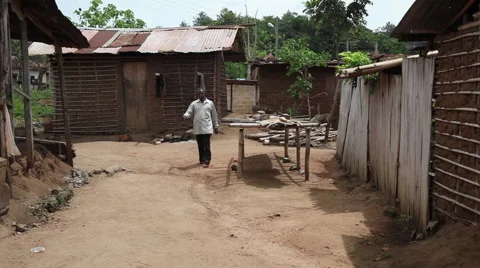 MAN WALKS PAST RUSTIC HOUSES Stock Footage 59864337