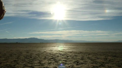 A man walks into the rising sun in a harsh desert landscape Stock Footage 55845909