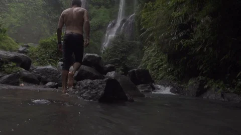 Man Walks Up River Towards Waterfall Slow Motion Stock Footage 106784567