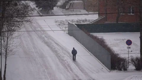 Man walks on road in snow Stock Footage 69115949